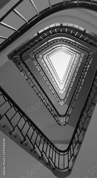 Fototapeta Abstract black and white high angle shot of a five floor vintage spiral staircase with a glass roofing in a triangular form.