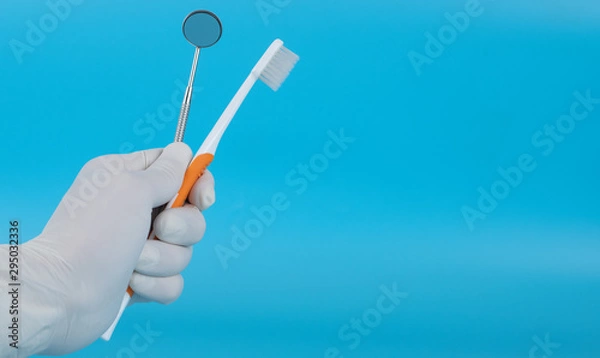 Fototapeta The dentist holds a mounted mirror to show the patient's dental examination.