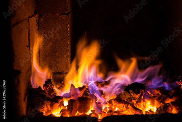 Fototapeta Bright fire burns on coals close-up. Carbon dioxide flies out with a blue spark.