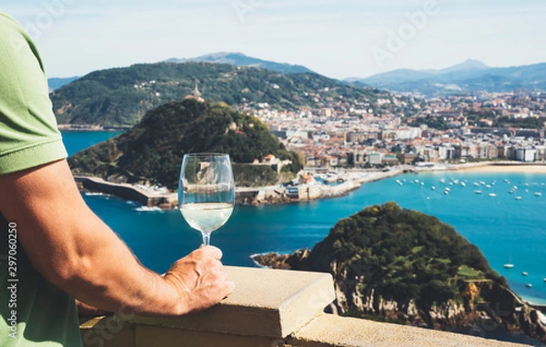 Obraz Drink glass white wine top view city coast yacht from observation deck, romantic tourist man toast with alcohol panoramic cityscape downtown, person tourism san sebastian vacation enjoy travel