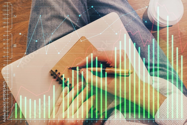 Fototapeta Double exposure of hands writing in notepad with stock market chart.