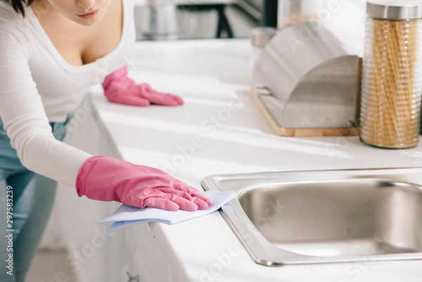 Fototapeta cropped view of housewife wiping kitchen tabletop with rag