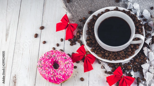 Fototapeta A hot cup of coffee with a doughnut and the coffee beans on the table. Composition of a delicious coffee and sweet snack.