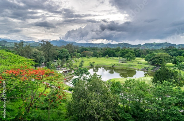 Fototapeta Massive green park, pond, and golf course in Clark Freeport Zone, with tropical forest and misty mountains in the background - Pampanga, Luzon, Philippines 