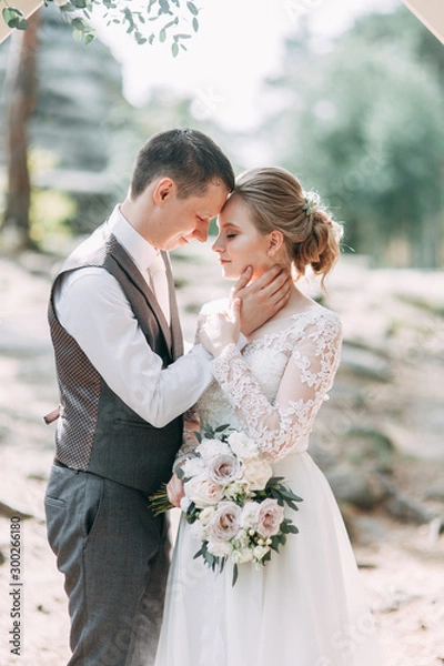 Fototapeta Beautiful couple at sunset in the Park. Wedding ceremony with arch in the forest.