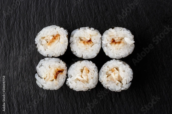 Fototapeta Maki Sushi Rolls with eel on black stone on dark background. Sushi menu. Japanese food. Closeup of delicious japanese food with sushi roll. Horizontal photo