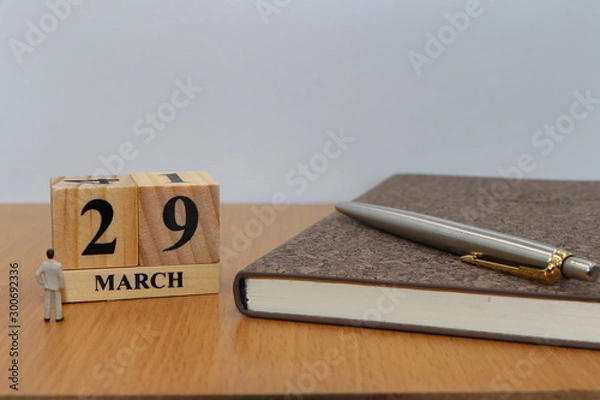 Fototapeta March  29, a calendar photo from the wood The table top consists of a book and pen that is ready to use. White background