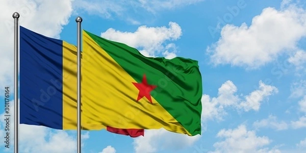 Fototapeta Romania and French Guiana flag waving in the wind against white cloudy blue sky together. Diplomacy concept, international relations.