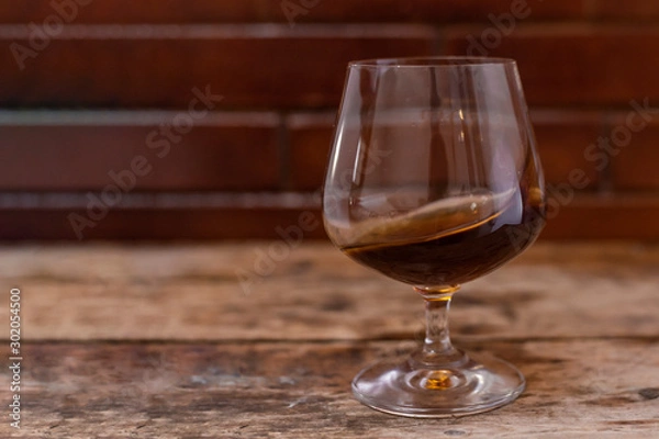 Obraz Glass of strong cognac drink on wooden background.