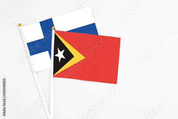 Fototapeta East Timor and Finland stick flags on white background. High quality fabric, miniature national flag. Peaceful global concept.White floor for copy space.