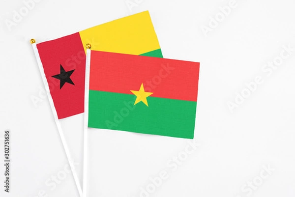 Fototapeta Burkina Faso and Guinea Bissau stick flags on white background. High quality fabric, miniature national flag. Peaceful global concept.White floor for copy space.