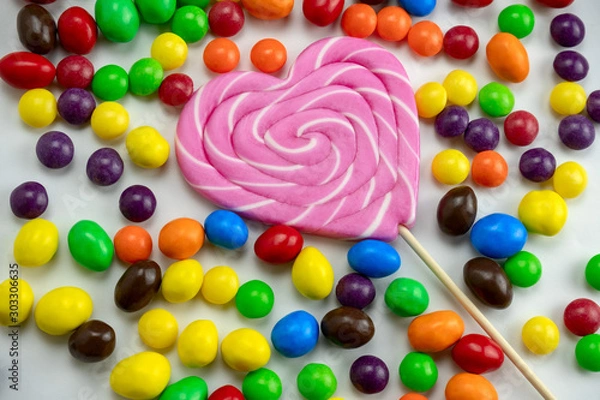 Fototapeta colourful candies and pink lollipop  on a white background close up selective focus, unhealthy eating and kids party food concept