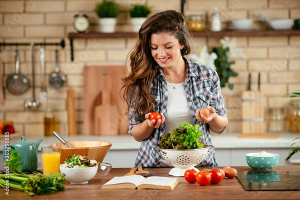 Fototapeta Young woman in kitchen. Beautiful woman making healthy food.