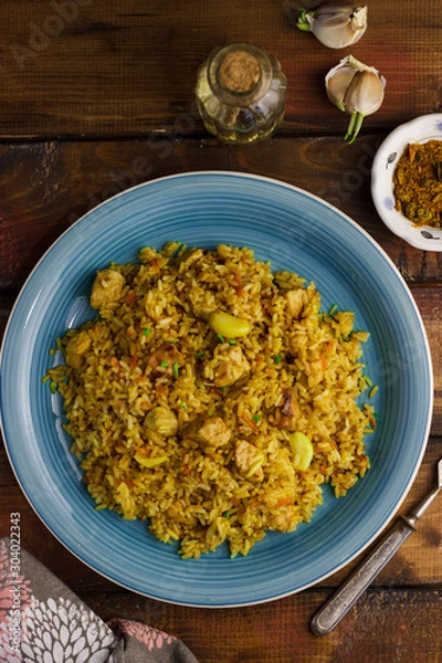 Fototapeta Pilaf with mint in a blue plate on a wooden background. Copyspace 