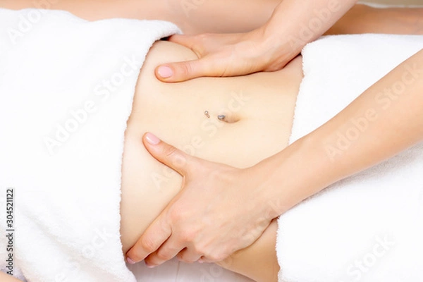 Fototapeta Massage Therapist Massaging a Womens Stomach. Massage and body care. Spa body massage woman hands treatment.