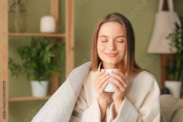 Fototapeta Young woman with cup of hot tea resting at home