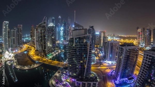 Fototapeta Aerial view of Dubai Marina residential and office skyscrapers with waterfront night timelapse