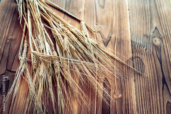 Fototapeta Wheat ears on rustic wooden background.