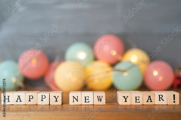 Obraz Happy New Year text made out of wooden blocks. Festive new year's eve decoration in the background. Copy space in the top.