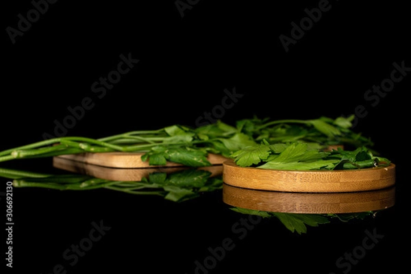 Fototapeta Lot of whole lot of pieces of fresh green parsley on round bamboo coaster on wooden cutting board isolated on black glass