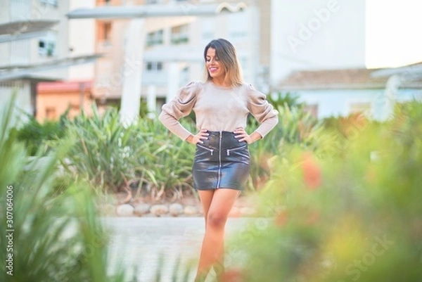 Fototapeta Young beautiful woman wearing sweater and skirt standing at the town street