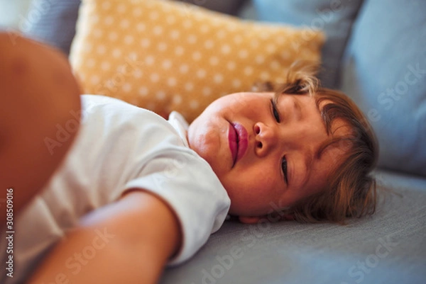 Fototapeta Beautiful toddler child girl wearing white bodysuit lying down on the sofa