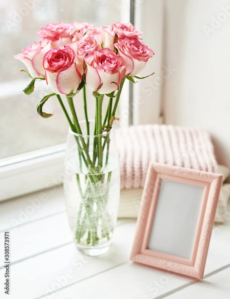 Fototapeta Bouquet of roses and photo frame on window. Valentine Card. Composition with fresh flowers. Space for text. Mother's day and March 8 card