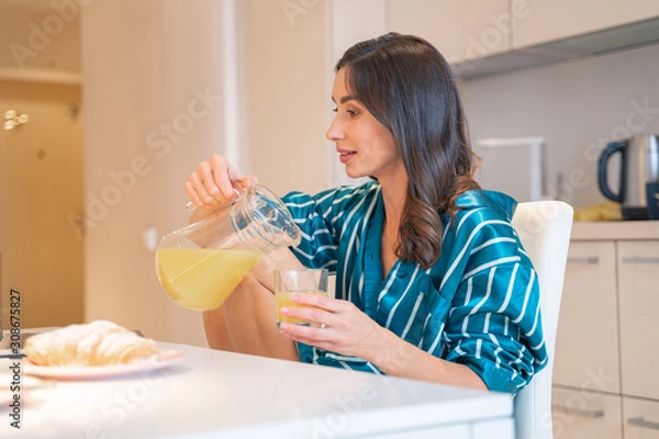 Obraz Calm woman pouring juice in the kitchen stock photo