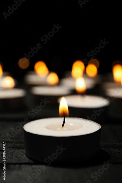 Fototapeta Group of burning candles on black background, close up