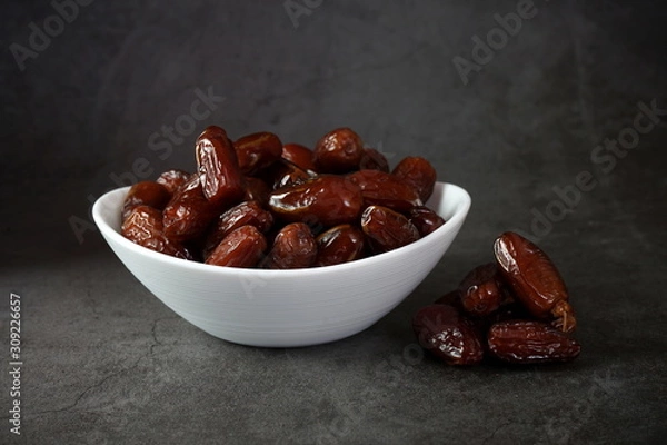 Fototapeta Dried dates in a bowl on a dark background