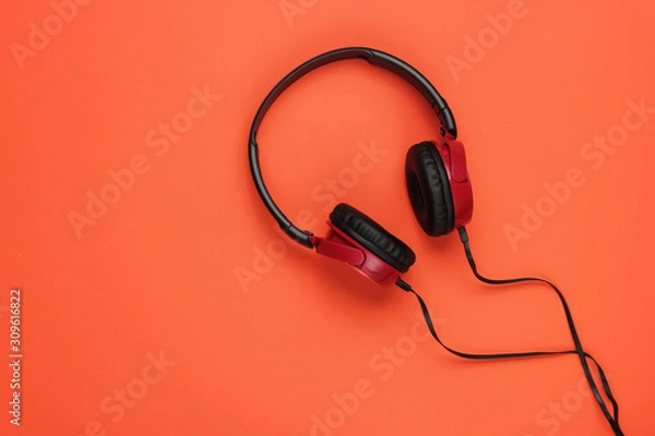 Fototapeta Modern wired headphones on orange background. Music lover concept. Top view