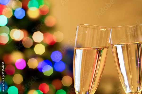 Fototapeta Blurred christmas tree and two glasses with sparkling wine champagne