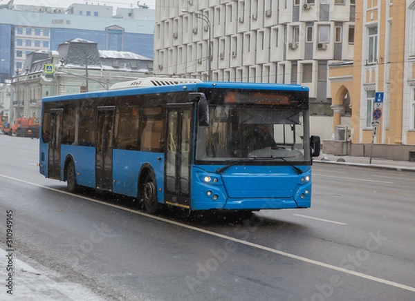 Fototapeta autobus porusza się zimą w mieście podczas opadów śniegu