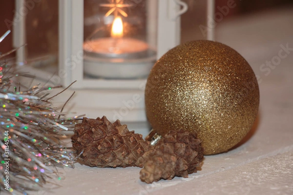 Fototapeta Christmas and New Year's background with candles, fir cones and beads on an old wooden table in rustic style, toned image.