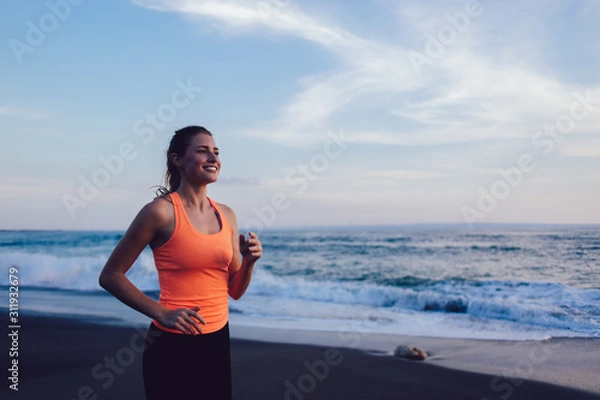 Fototapeta Sportive young woman jogging on beach