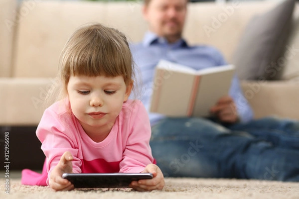 Fototapeta Father and daughter lie on floor using mobile phone