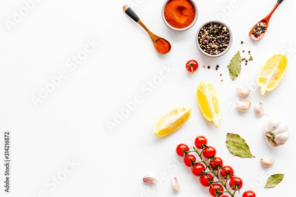 Fototapeta Cooking background with spices, vegetables - pepper, garlic, cherry tomatoes - on white desk top-down frame copy space