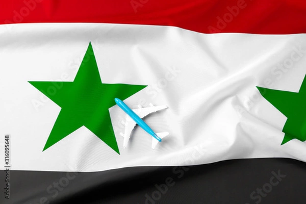 Fototapeta Small toy plane over the fabric flag of Syria