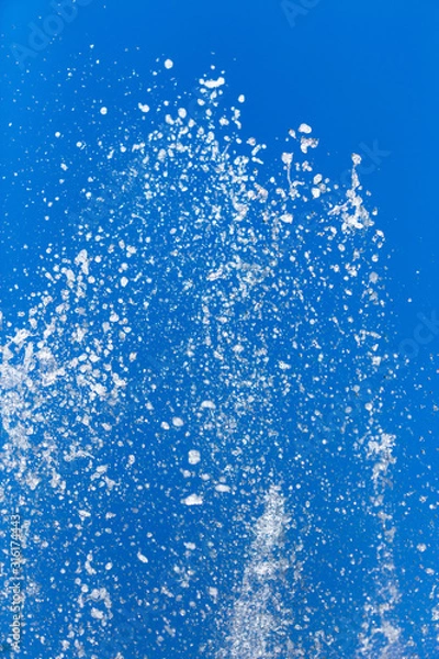 Fototapeta Splashing water from a fountain on a background of blue sky