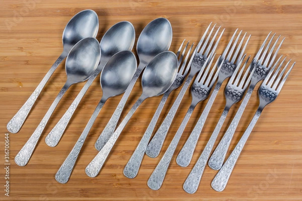 Fototapeta Stainless steel eating utensils on wooden surface, top view