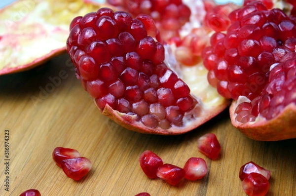 Fototapeta Open pomegranate with peel on a wooden table