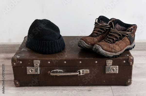 Fototapeta vintage suitcase, winter hat, leather jacket and boots over white wall background