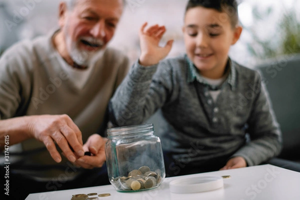 Fototapeta Grandpa and grandson saving money. Grandfather teaching grandchild how to save money.  