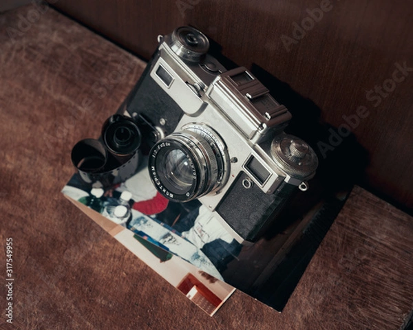 Fototapeta Vintage camera with old pictures and film roll on wood table