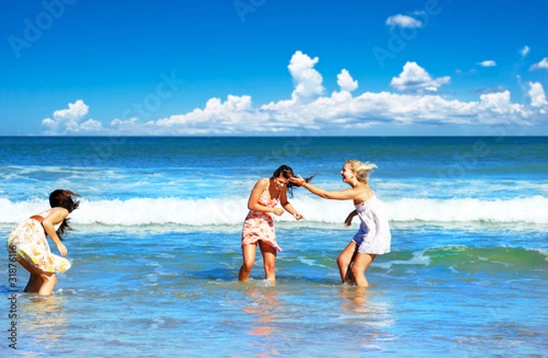 Fototapeta Three young woman having fun on the beach on a summer day