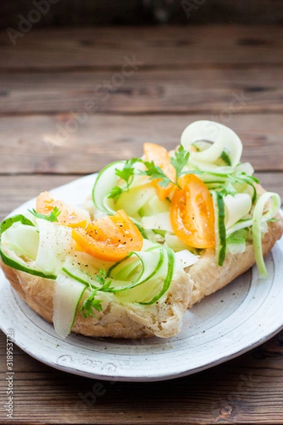 Fototapeta Bruschetta with cream cheese, fresh zuccini slices, yellow tomatoes, herbs and pepper on wooden background. 