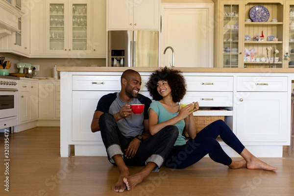 Fototapeta Happy young couple sitting in the kitchen