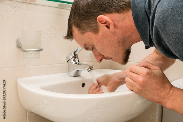 Fototapeta Young man washing face. Bathroom.