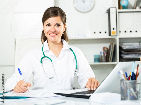 Obraz Smiling woman doctor working effectively in her office