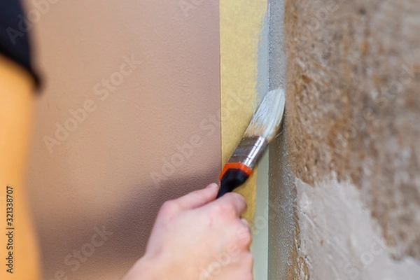 Fototapeta hand paints the wall with a brush